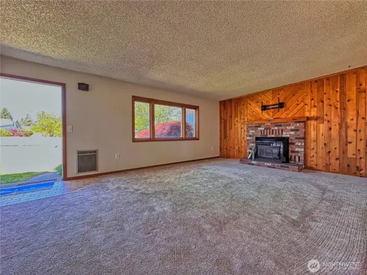 An inviting living room is anchored by a cozy fireplace insert and wood accent wall.