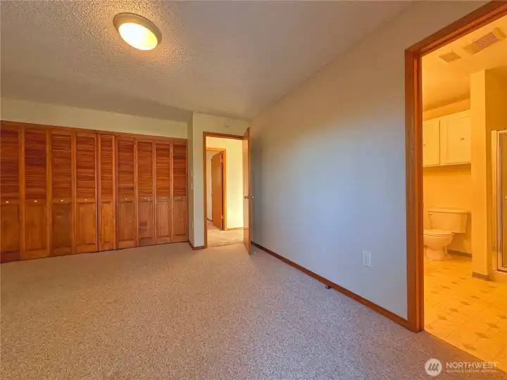 Primary bedroom has closet wall with wire closet organizational system and private 3/4 bathroom.