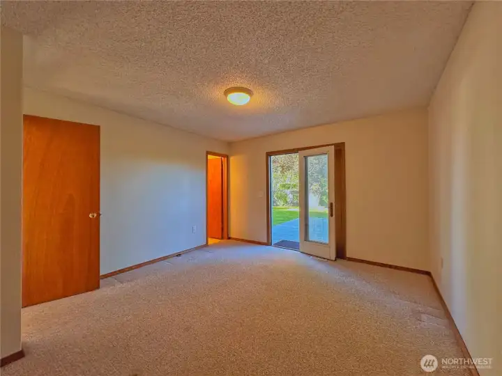 Primary bedroom features French doors opening directly to the deck and backyard, creating a peaceful private retreat space.