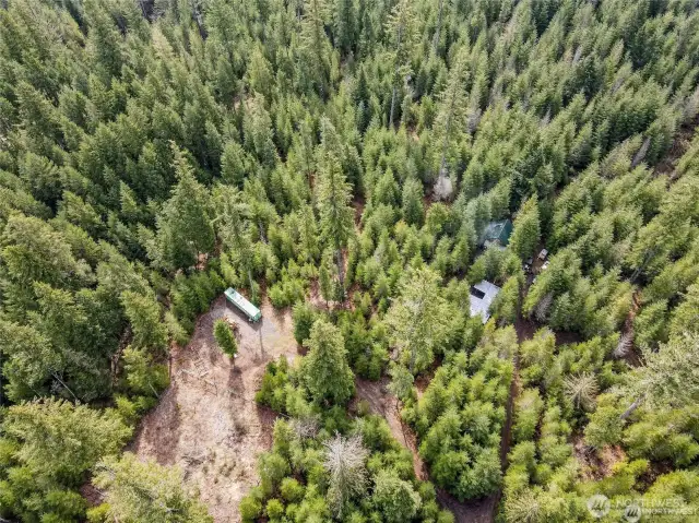 Property largely treed, with cleared area for storage container and fenced garden area