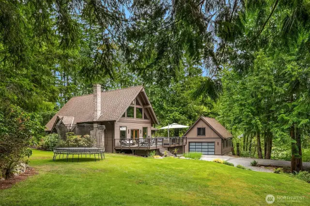 This home features new landscaping and is framed by towering fir trees.
