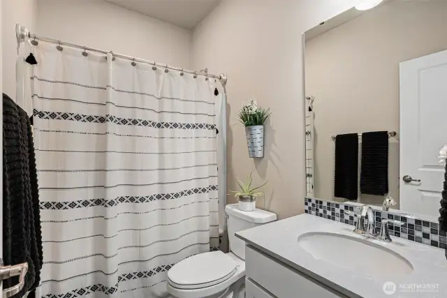 Main floor full bathroom w/quartz counter top & tile backsplash.