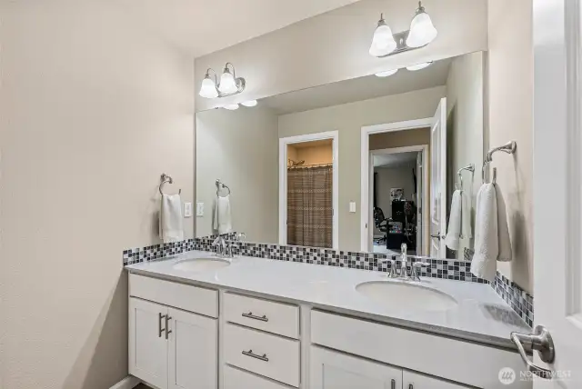 Full bathroom w/double vanity, quartz counter tops w/tile backsplash, tile floors & private toilet/shower space.