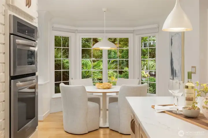 Bright breakfast nook wrapped in windows overlooking lush gardens