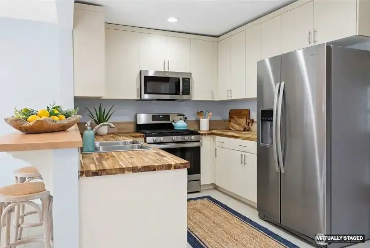 Virtually Staged Kitchen offer updated cabinetry, butcher block countertops, fixtures, and stainless steel appliances.