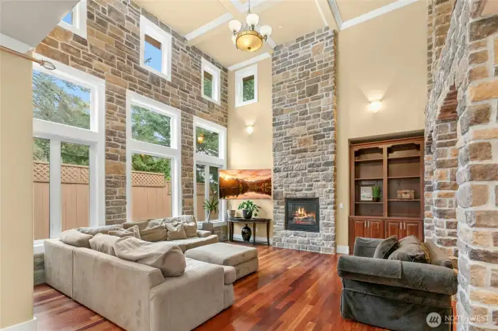 Impressive floor-to-ceiling genuine stone fireplace showcased by soaring 18-foot ceilings, creating a dramatic focal point