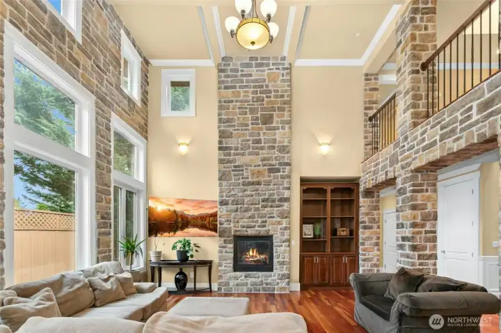 Impressive floor-to-ceiling genuine stone fireplace showcased by soaring 18-foot ceilings, creating a dramatic focal point