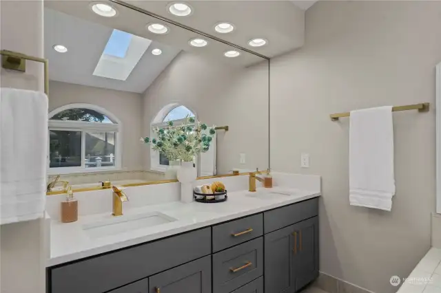 The updated vanity in the primary bathroom is complemented by a skylight, which floods the space with beautiful natural light. The combination of these elements enhances the overall ambiance, creating a bright and welcoming atmosphere.