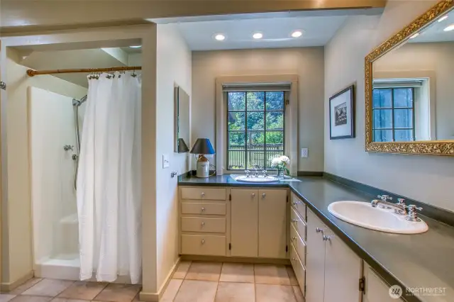 Spacious en-suite bath with a shower in the main-level primary bedroom.
