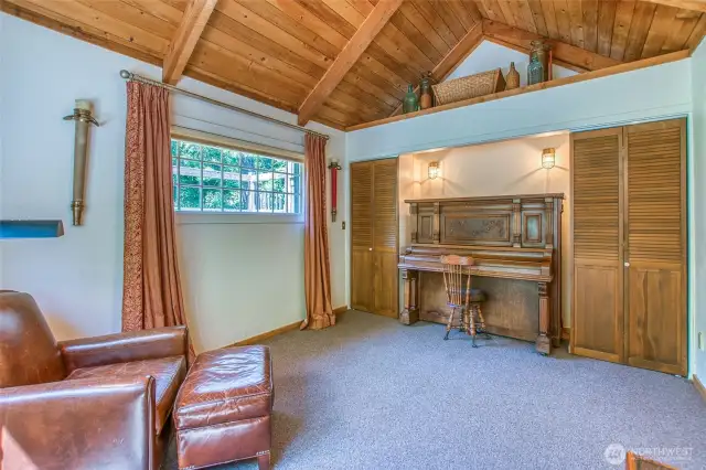 Downstairs guest bedroom or office with vaulted wood ceilings and garden views, featuring warm natural light.