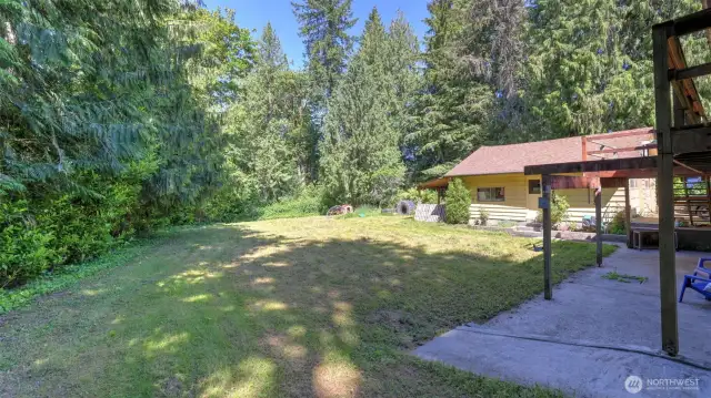 This expansive open area, wrapped in mature trees and lush greenery, offers an ideal setting for recreation, play, and enjoying the outdoors