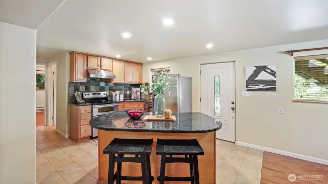 Enjoy cooking in a kitchen with granite counters, eye-catching backsplash tiles, and durable tile flooring.
