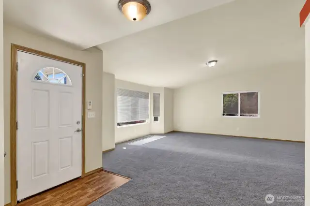 Vaulted ceilings, new carpet, and a wall of south-facing windows fill the space with natural light, creating a bright and airy feel."