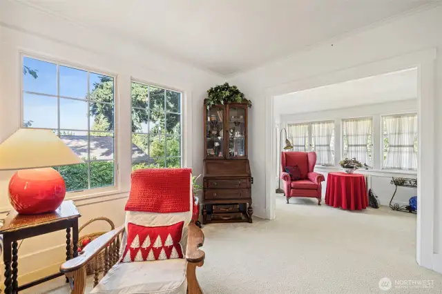 A light and bright living room has beautiful picture windows overlooking the delightful yard.