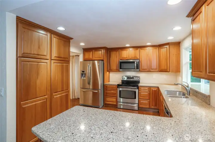 Rich cherry cabinets extend throughout the kitchen, adding both warmth and elegance, with generous counter space for all your meal preparation. The kitchen is finished with sleek stainless steel appliances.