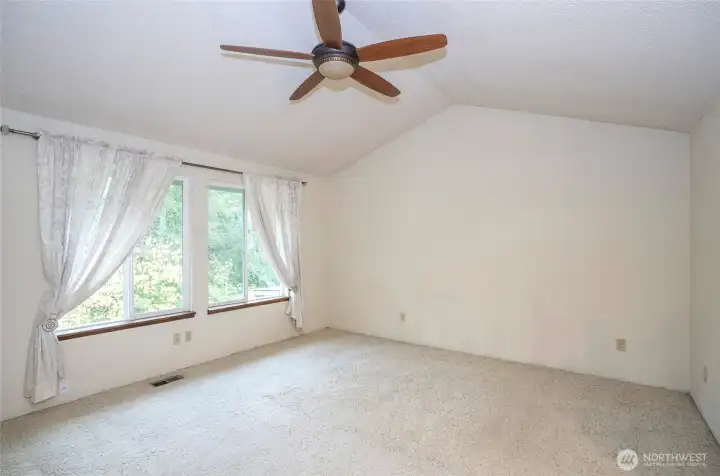 Upper-level primary suite featuring vaulted ceilings and two large picture windows.