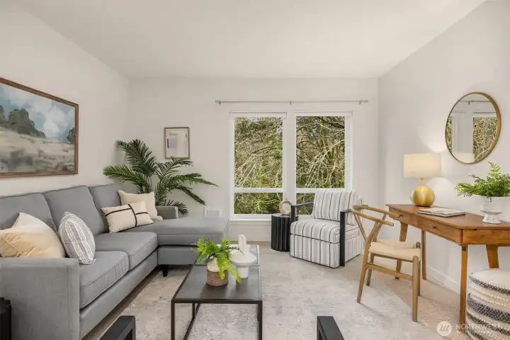 Bright and comfortable living area with large windows framing tranquil tree-lined views and abundant natural light.