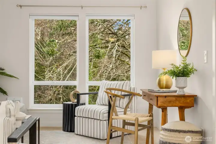 Corner seating vignette framed by oversized windows, creating a bright and inviting space ideal for reading, working, or relaxing.