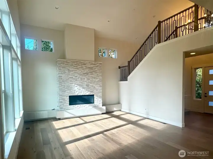 Great room has soaring ceilings and stacksone faced linear gas fireplace and a raised tile hearth.