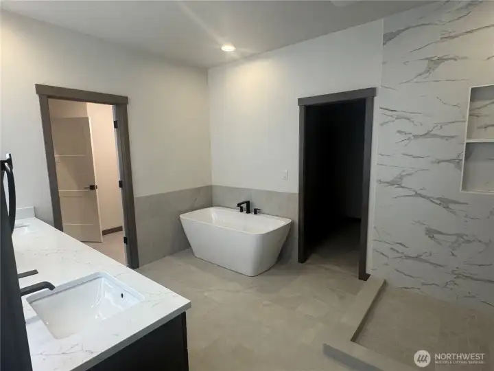 Primary Suite bath.  offers tile floors and direct access to walk in closet and laundry room.