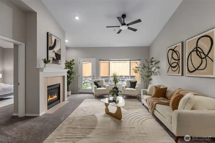 Bright living room with gas fireplace, ceiling fan and vaulted ceilings.