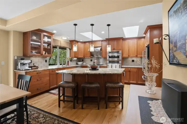 Rich cherry cabinetry decorates the kitchen and is evident throughout this home. A nicely-sized kitchen island is enhanced with gorgeous granite countertop and is a baker's delight with a pull-up-and-out shelf made specifically for a heavy mixer. Stainless steel appliances remain with the home, and skylights add to the natural light that is appreciated here.