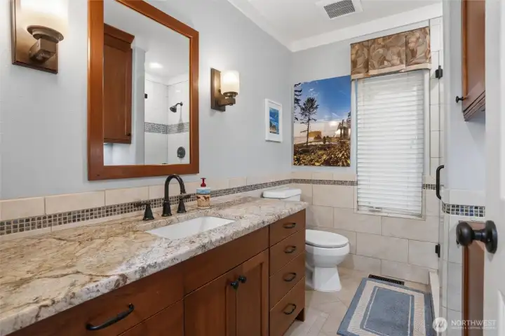 The guest bath on the main level includes a shower, beautiful cherry cabinets and granite countertops, keeping the same theme throughout. Tile flooring and no-edge sink makes for easy cleanup.