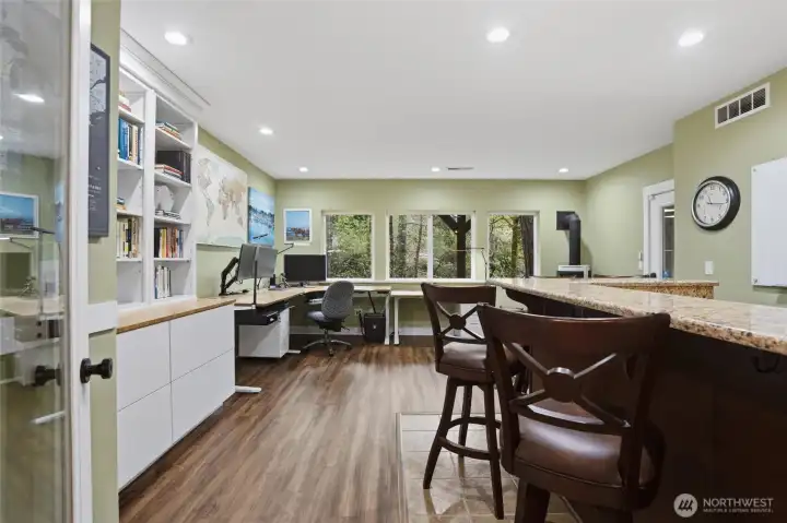 A flexible bonus room in the lower level enjoys laminate and tile flooring, built-in shelving and cabinets, as well as a large wet bar with granite counter tops.  A door to the exterior is also accessible from this room. To keep things cozy, a gas Norwegian Jotul stove was installed. The large windows in this room have a lovely tree and territorial view.