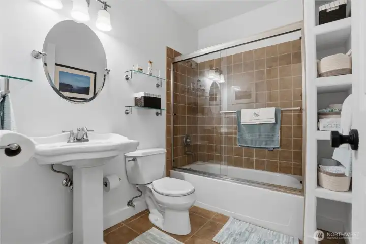 The guest bath in the lower level includes a shower/tub combo, tile flooring, and pedestal sink.