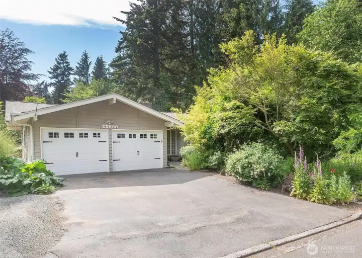 Two car garage with additional parking in driveway and beside.