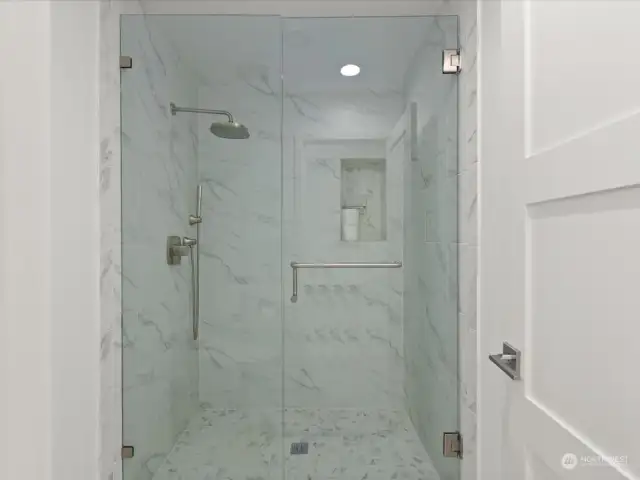 Separate shower with custon tile, built-in shelf and glass enclosure.