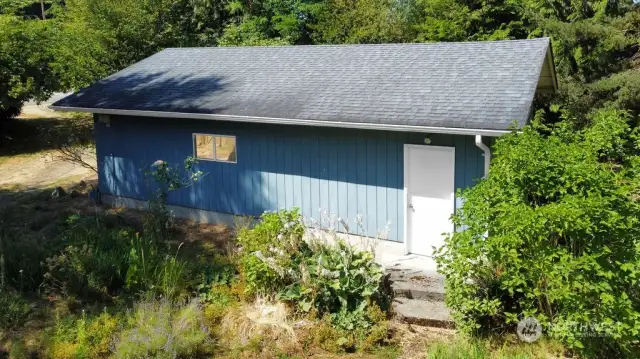 side door to garage with beautiful flower beads & blueberry bushes