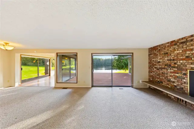 Living room with expansive deck overlooking the tranquil lake. Propane fireplace for cozy evenings!