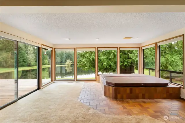 Primary bedroom with indoor hot tub and captivating views of the lake. Sliding door to deck.