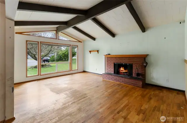 Large front room with vaulted ceilings and a cozy wood fireplace.  Real hardwood floors!