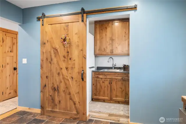The laundry space & 1/2 bath with extra storage is conveniently located just off of the kitchen, hidden by a cute barn door!