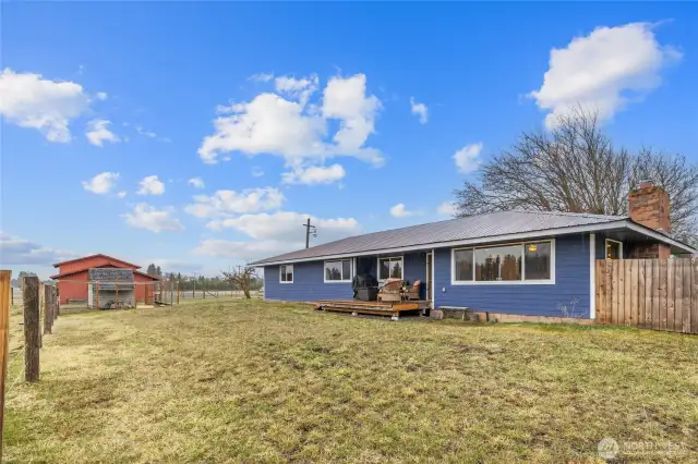 Rear exterior of home, showing the expanded deck & fenced front yard.