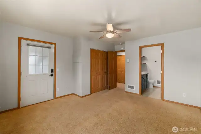 Primary bedroom has a ceiling fan, door allowing exit to back covered deck, and adjoining bathroom