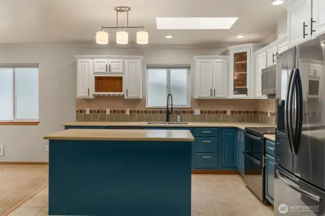 View of kitchen with Corian counters, newly updated cabinets, newly updated appliances, and lighting. Note the skylight in the kitchen.