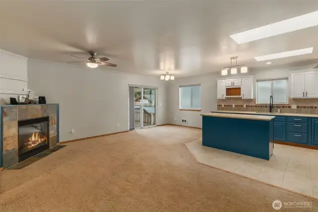 View of living area with gas(propane) fireplace and tile mantel. Also, note another skylight over the kitchen area.