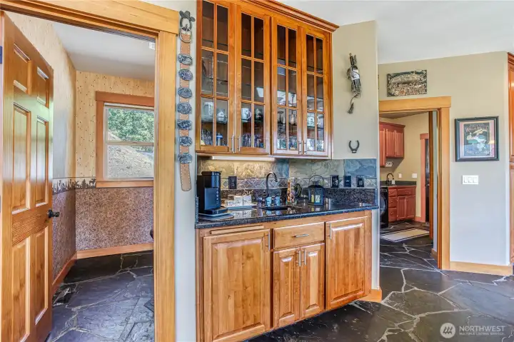 Coffee wet bar next to the kitchen has display cabinets above & plenty of storage. Slate flooring throughout the laundry entry to the half bath