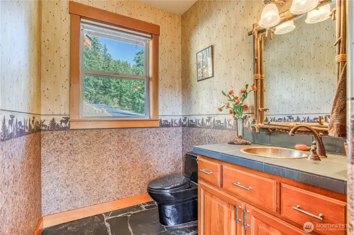 Half bath off the living area has a window to the driveway side, slate flooring, ceramic tile counter, & beautiful copper sink.
