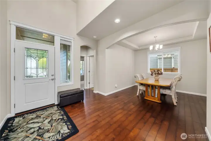 Bright and airy entry flows into a versatile dining space, highlighted by vaulted ceilings and rich engineered hardwood flooring.