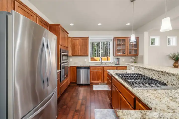 Well-designed kitchen offers generous granite slab counters, stainless steel appliances, and effortless flow for cooking and entertaining.