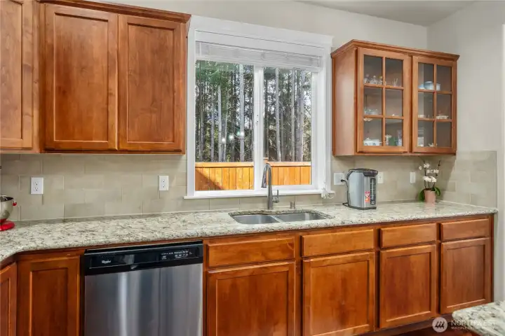 Stainless steel dishwasher, double sink, and glass-front cabinets—perfect for showcasing your favorite pieces while maintaining a functional workspace.