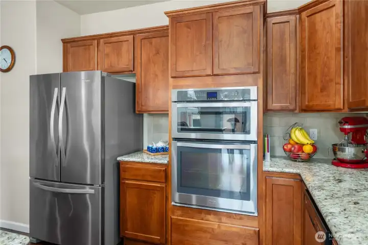 Stainless steel refrigerator & built-in microwave/oven paired with rich cabinetry and granite countertops creates a clean, cohesive kitchen design.