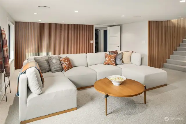 Lower level theater room with speakers and acoustical white oak panels.