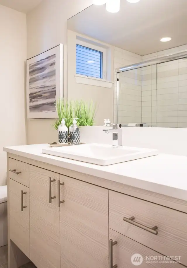 Main level bathroom compete with soft-closing Belmont cabinetry, quartz counters and backsplashes, tiled flooring and tiled large showers.