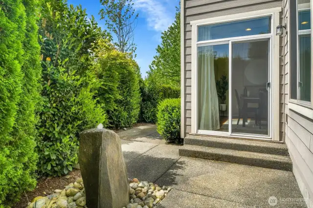The peaceful patio is surrounded by greenery and has a lovely fountain.