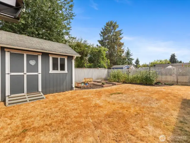 Expansive outdoor spaces with fully fenced Yard, Garden, Raised Beds & Outbuilding/Shed.